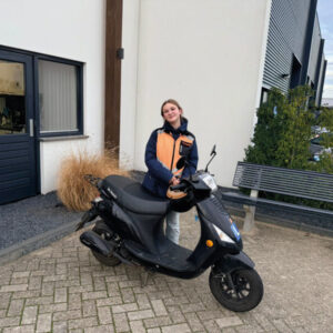 Leerling in een veiligheidshesje achter een lesscooter van Mayar